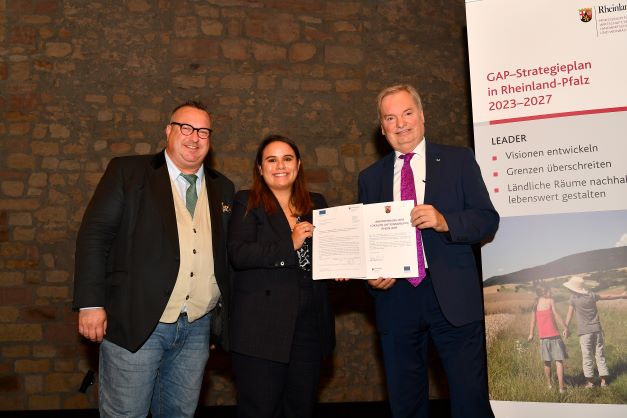 Landwirtschaftsstaatssekretär Andreas Becht, LEADER-Managerin Rocio Fernandez Suarez und Vorsitzende der LAG Rhein-Wied und Bürgermeister der VG Unkel Herr Karsten Fehr bei der Überreichung der Urkunde Bildnachweis: Wirtschaftsministerium RLP / Kristina Schäfer